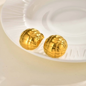 Detailansicht goldener Halbkugel-Ohrringe mit Gittergravur auf einer Keramikschale