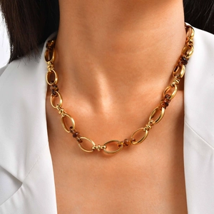 Dettaglio delle maglie ovali dorate e perline in resina marmorizzata su una collana