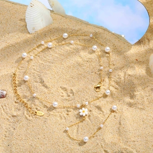 18K gold plated Y-necklace with pearls and white flower pendant on a beach setting