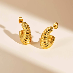 Detailed view of twisted croissant hoop earrings in polished gold with spiral texture