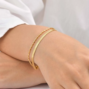 Close-up of golden double-layer bracelet with snake chain and cylinder bead textures