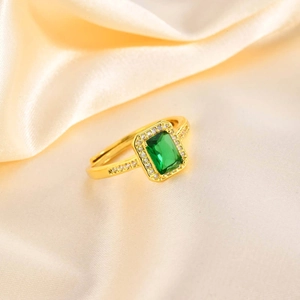 Macro detail of gold adjustable ring with emerald cut green zircon and halo setting
