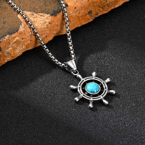 Detailed shot of a vintage rudder pendant with turquoise stone on a stainless steel box chain