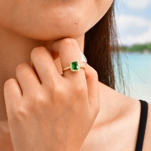 Detailed close-up of a gold-plated ring featuring a rectangular emerald zircon on a hand