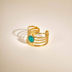 Detailed view of a multi-layer gold cuff bracelet with a round turquoise center stone