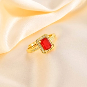 Detailed macro view of an adjustable gold ring featuring a red rectangular gemstone