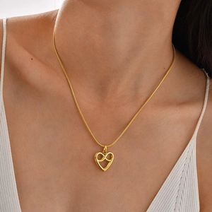 Detail of infinity heart pendant on gold snake chain worn by a female model