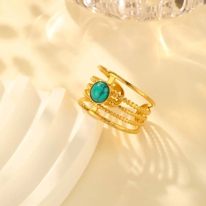 Detail of gold open ring with turquoise stone and wave patterns on a textured stand