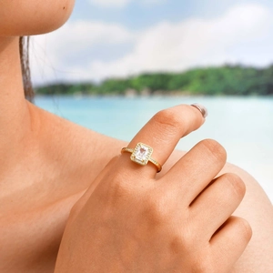Detailed shot of an adjustable gold ring featuring a large rectangular zircon on a beach