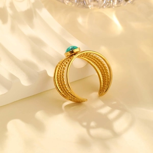 Detailed view of gold multi-layer ring with round turquoise on white wave background