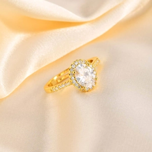 Detail of adjustable gold ring featuring a halo-set green zircon on beige silk