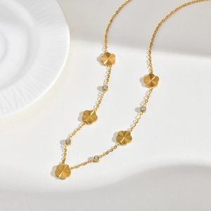 Detailed close-up of golden stainless steel bracelet with floral charms and zircons