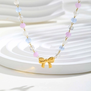 Macro d'un collier de perles colorées avec pendentif nœud doré sur support design