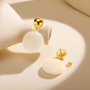 Boucles d'oreilles boules dorées minimalistes avec disques de résine blanc crème sur beige