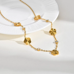 Golden stainless steel necklace featuring textured five-leaf flower charms and zircon stones