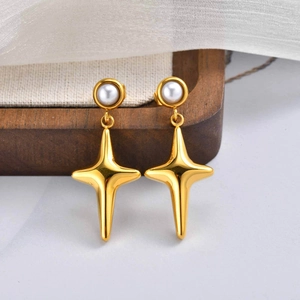 Macro detail of gold stainless steel star earrings with white pearl studs