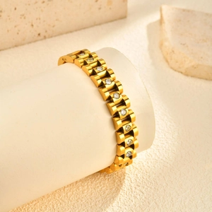 Macro shot of gold watch-band style bracelet with inlaid cubic zirconia on white stand