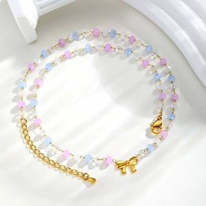 Détail d'un collier de perles colorées avec pendentif nœud doré et chaînette