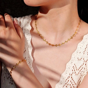 Set collana e bracciale dorati con design a fiori indossati da una modella elegante