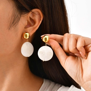 Détail de perles dorées et boucles d'oreilles en résine marbrée sur un modèle