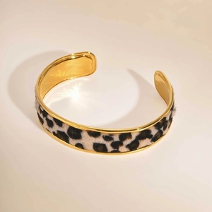 Detailed view of wide golden bangle featuring a luxurious leopard print texture inlay