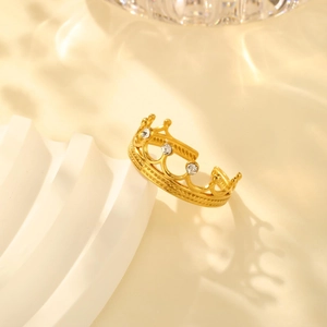 Detailed view of an 18K gold plated crown ring with zircon on white architectural props