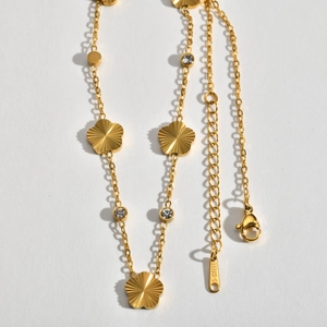 Detail of gold stainless steel necklace with five-leaf flowers and round zircon charms