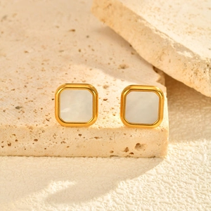 Macro shot of gold square stud earrings with white mother of pearl inlay on stone