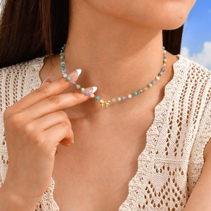 Détail du collier à nœud avec perles colorées porté sur un haut en dentelle blanche