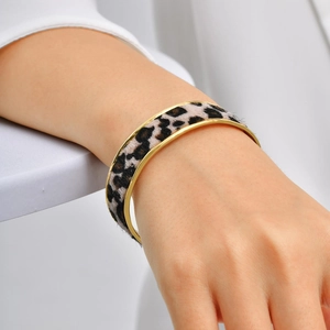 Detail of golden stainless steel cuff bracelet with textured leopard print inlay