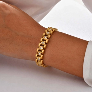 Close-up of golden watch-style link bracelet featuring sparkling inlaid cubic zirconia