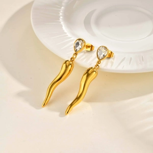 Macro detail of gold water drop zircon horn earrings on white ceramic dish