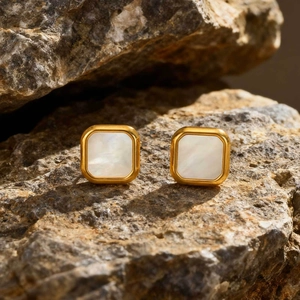 Macro view of square gold earrings featuring iridescent white mother of pearl inlay on rock