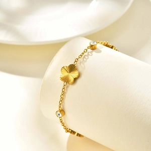 Detailed macro view of golden flower bracelet with clover charms and clear cubic zirconia