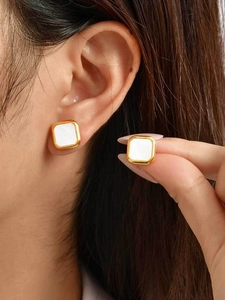 Close-up of gold stainless steel square stud earrings with white mother of pearl inlay