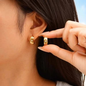 Goldene breite Creolen mit graviertem Blumenmuster und Zirkonia-Akzenten am Modell
