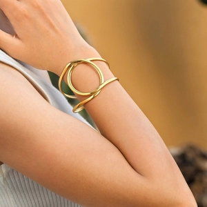 Detail shot of a double-layered gold geometric cuff bracelet worn on a female wrist