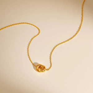 Collier minimaliste à doubles anneaux entrelacés dorés avec des détails texturés