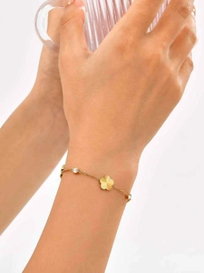 Detail of gold clover flower bracelet with zircon charms on a model's wrist