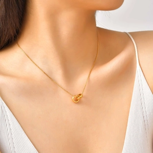Détail de cercles dorés imbriqués avec texture dentelée sur un collier à maillons fins