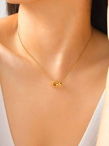 Détail du pendentif à deux anneaux entrelacés sur une chaîne dorée portée par un mannequin