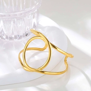 Detailed view of golden double-layer geometric cross ring bangle on minimalist stand