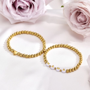 Detail of two-piece golden beaded bracelets with heart charm and MAMA letter beads
