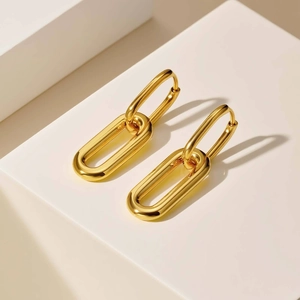 Macro detail of glossy gold dual oval link earrings on minimalist geometric platform