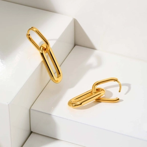 Close-up of gold oval linked earrings featuring a high-polish mirror finish on white steps