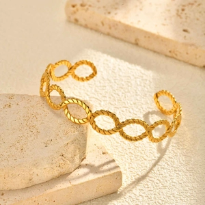 Detailed close-up of 18K gold-plated twisted oval link open cuff bracelet on stone