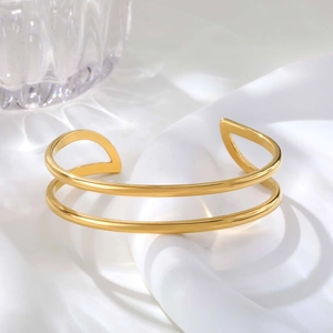 Detail of double-layer gold bangle with geometric open design on white silk background