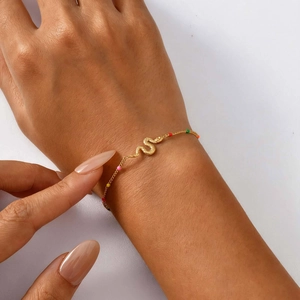 Detail of gold snake bracelet with colorful mini beads on a model's wrist