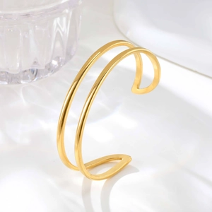 Detail shot of a double-layered geometric gold open bangle with polished mirror finish