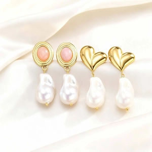 Detail of vintage gold earrings with pink stones and baroque pearls on silk